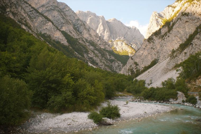 A clear mountain river in a deep gorge between pale limestone walls
